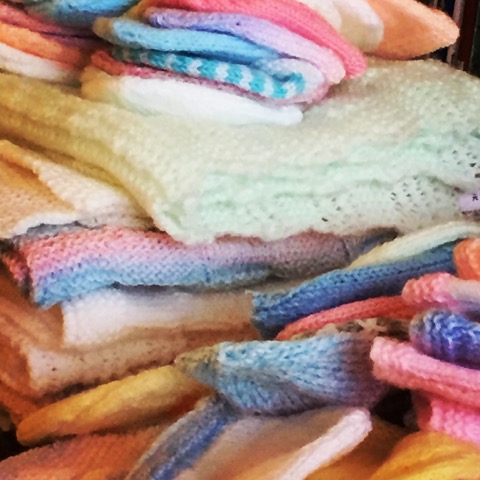 a pile of blue, pink and cream knitted blankets