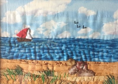 Image of the beach with rocks looking out to sea with a boat with a red mast and three birds. Created using folded fabric