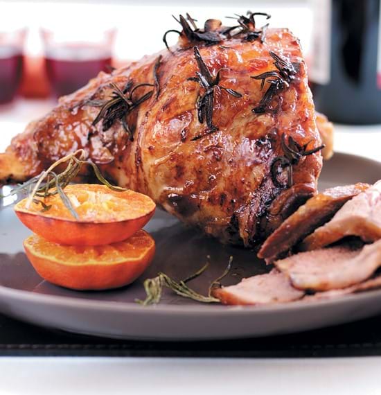 Image of roast lamb joint with rosemary and roasted oranges on a grey plate