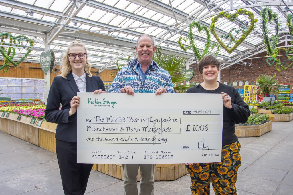 image of three people holding large cheque in greenhouse