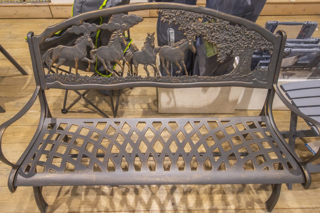 Cast iron bench with horse pattern carved out of the backrest.
