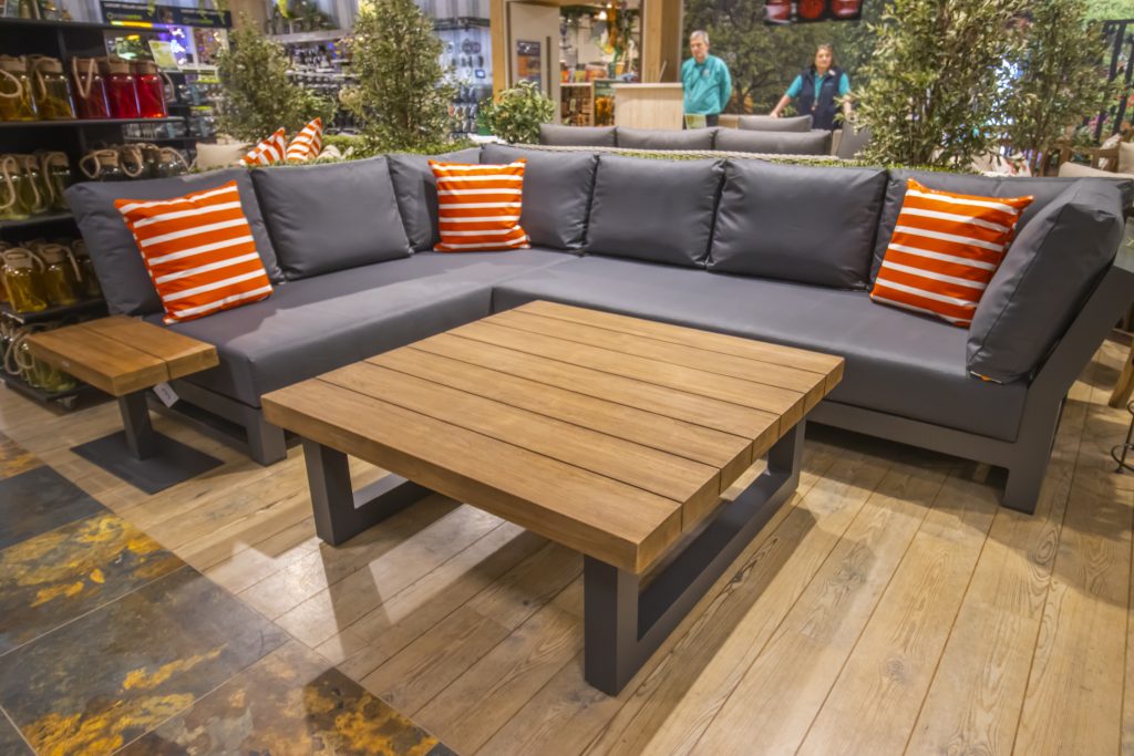 image of a grey large corner garden lounge set with orange stripped cushions with wooden table in the centre