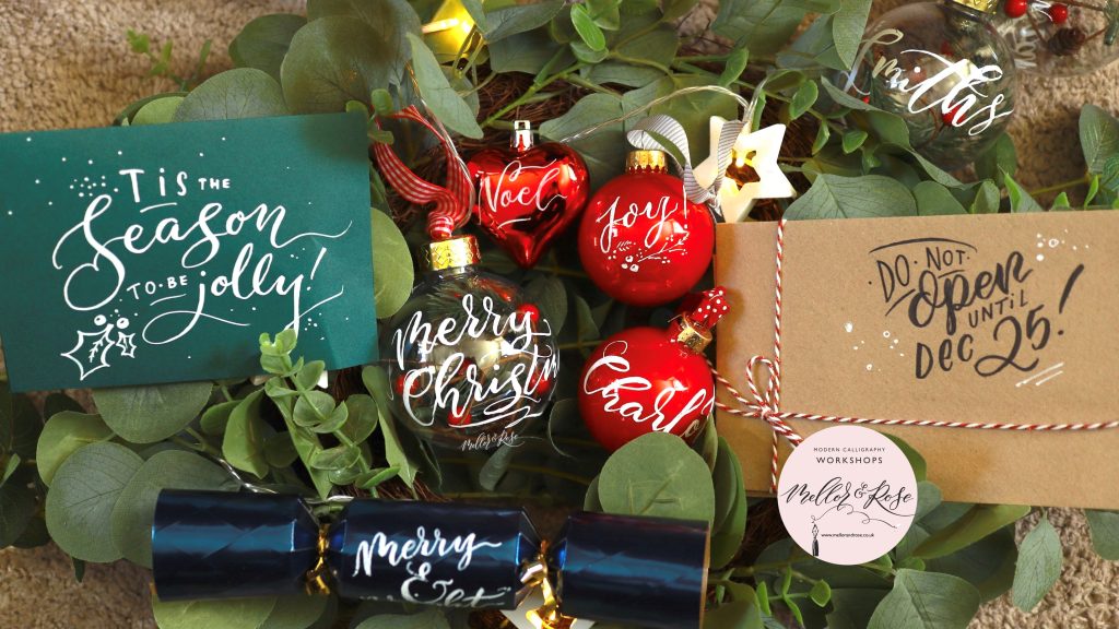 A collection of Christmas baubles, cracker and envelopes with calligraphy writing on